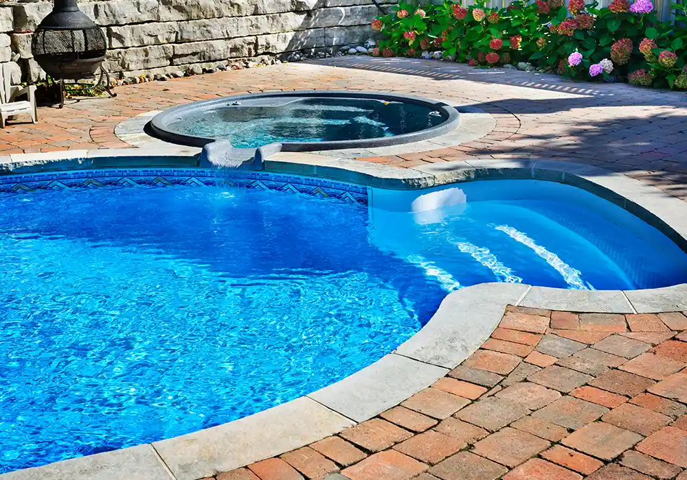 Paver deck around a freeform pool and spa