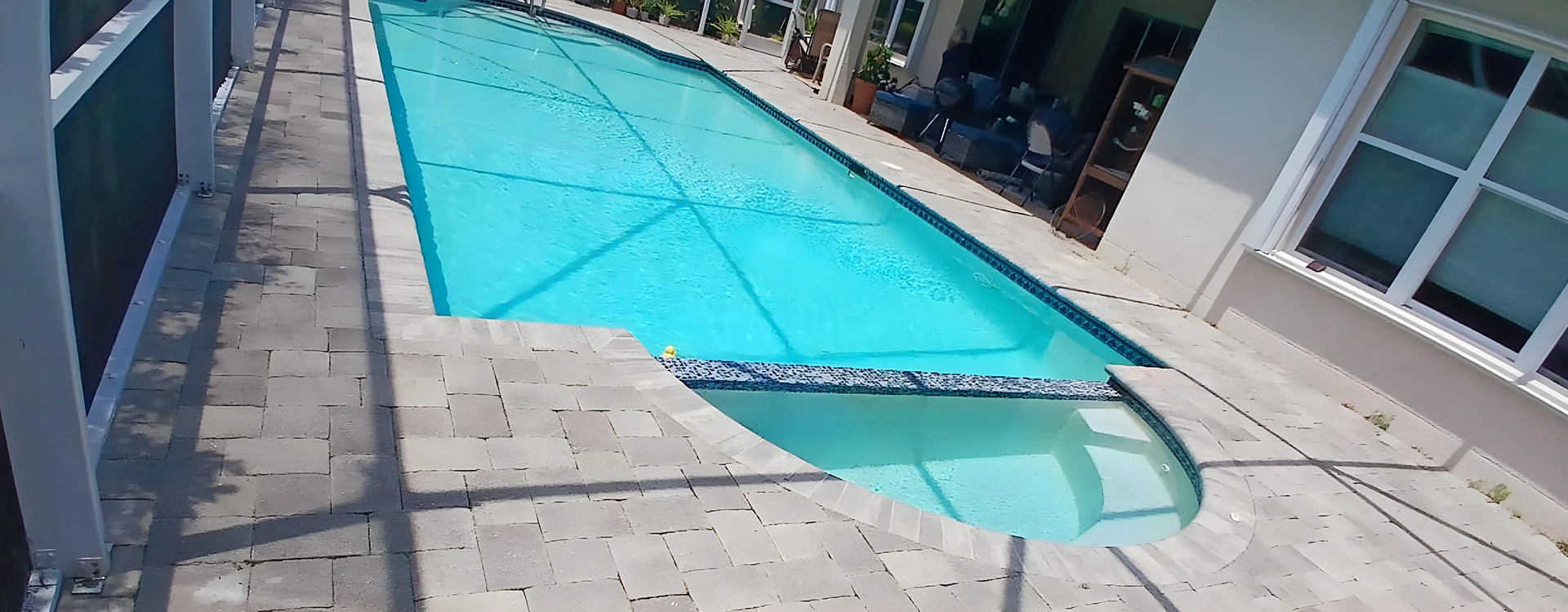 Paver pool deck surrounding a screened pool